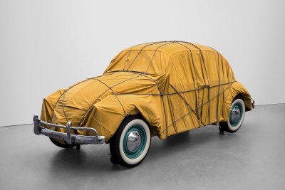 A Volkswagen Beetle wrapped ina brown fabric and tied with rope.