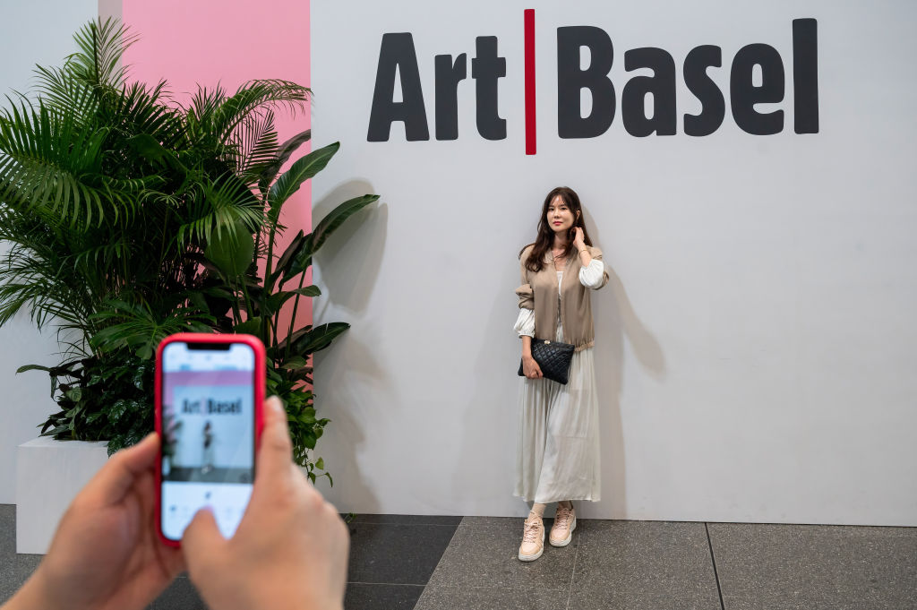 HONG KONG, CHINA - 2023/03/24: A visitor poses for a photo at the entrance of the Art Basel Hong Kong show after several years of remote and hybrid events due to covid restrictions in Hong Kong. (Photo by Sebastian Ng/SOPA Images/LightRocket via Getty Images)