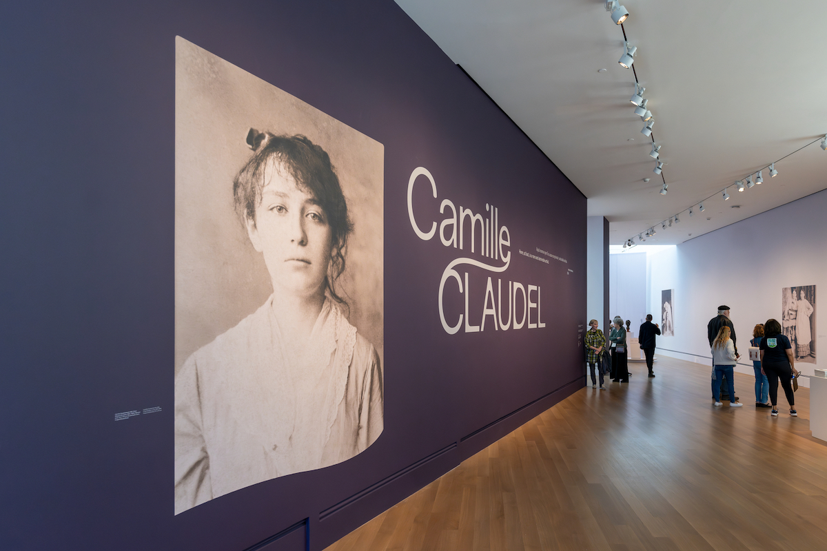 A photograph of a woman next to the words "Camille Claudel" on a purple wall.