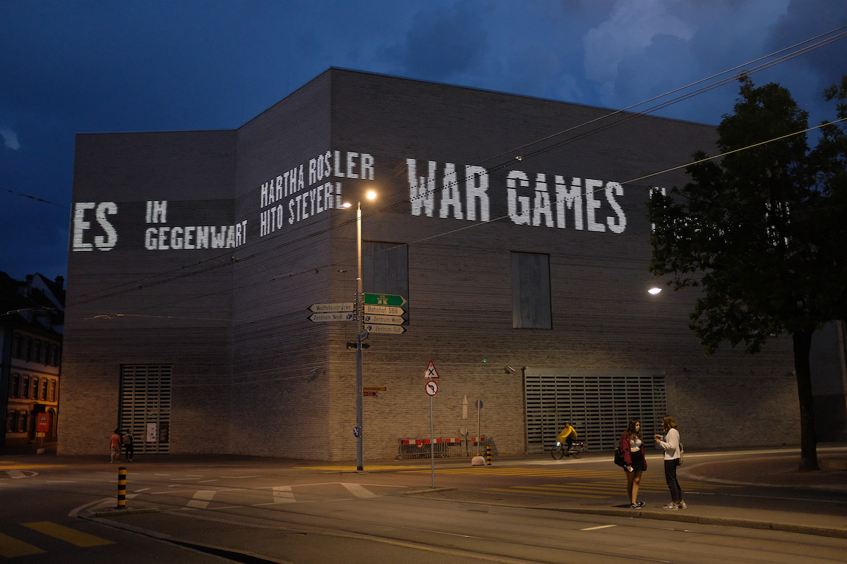 An angular museum at night with two people in front of it.