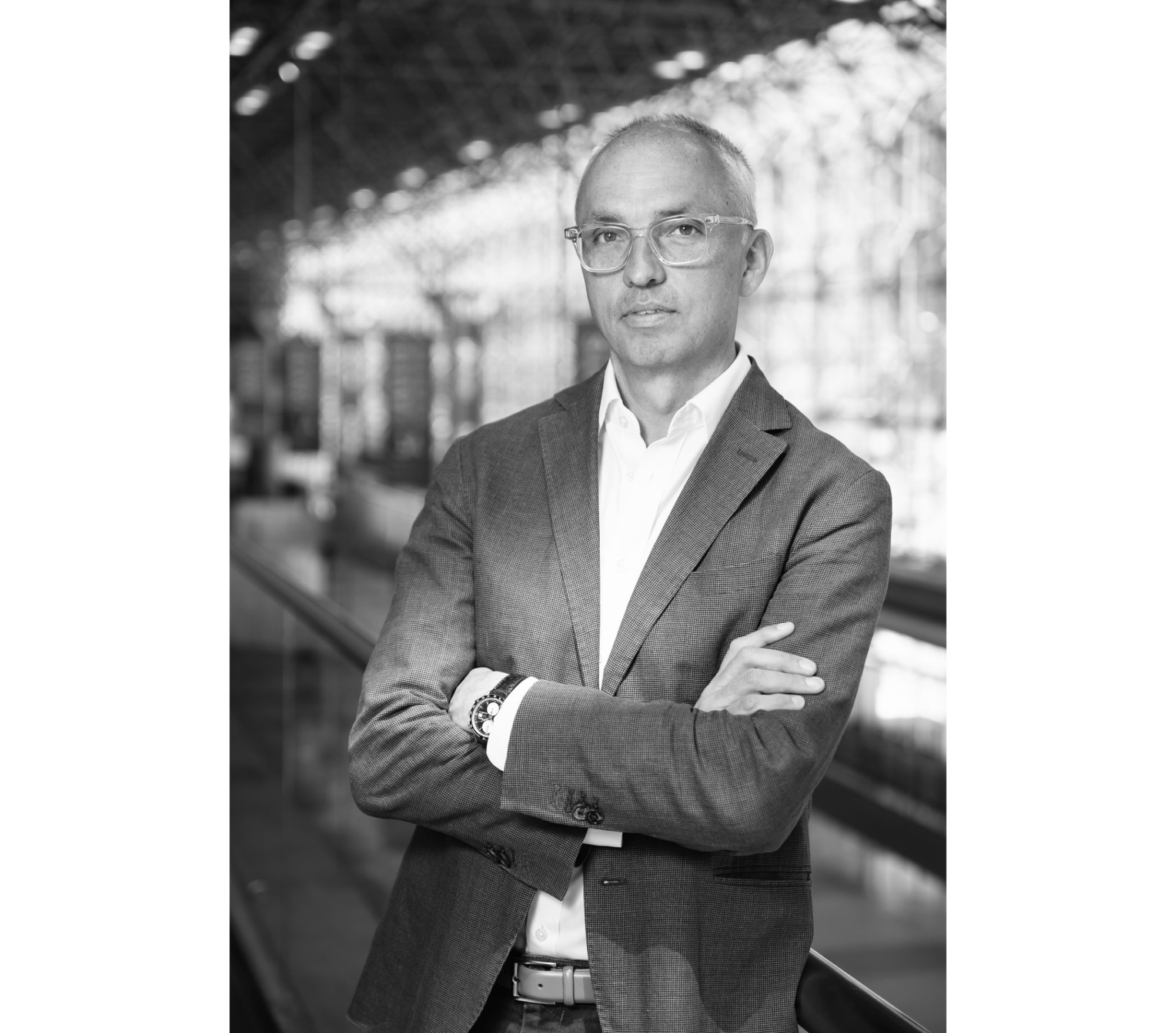 Black and white photo of Photofairs New York founder Scott Gray. He is wearing a suit jacket, glasses, a white dress shirt, and has his arms crossed.