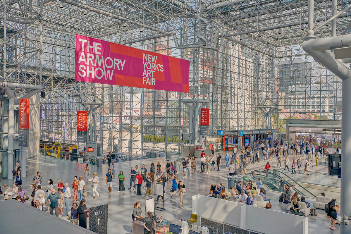 Aerial view of Javits Center, a steel and glass structure, with people waiting in line. Above is a banner that reads 'The Armory Show: New York's Art Fair'