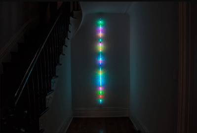 A thin reed-like straight multi-colored neon-light art object.